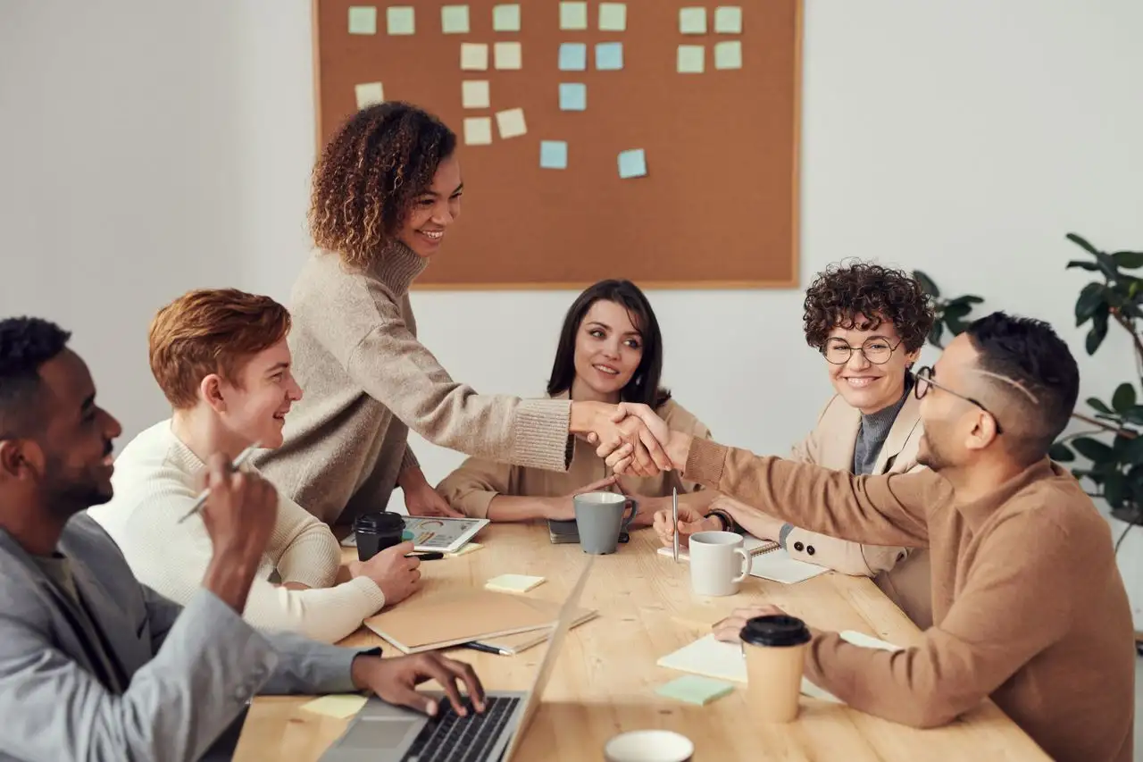 Colleagues shaking hands around a meeting table